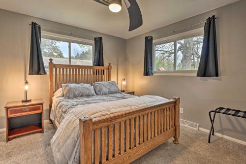 een slaapkamer met een houten bed en 2 ramen bij Warm Mosinee Home with Patio, Fire Pit and Grills in Mosinee