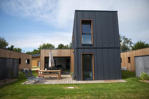 una casa negra con terraza y banco en Les Lodges de Beg Leguer - côte de granit rose, en Lannion