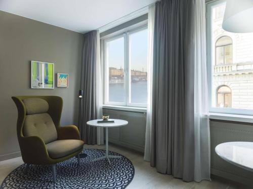 a room with a chair and a table and a window at Radisson Collection, Strand Hotel, Stockholm in Stockholm