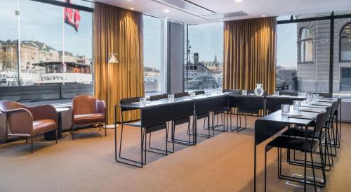 a restaurant with black tables and chairs and windows at Radisson Collection, Strand Hotel, Stockholm in Stockholm