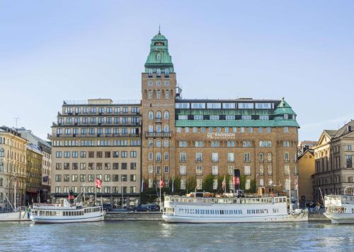 three boats in a river in front of a building at Radisson Collection, Strand Hotel, Stockholm in Stockholm
