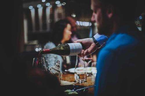 a woman is pouring a bottle of wine at Radisson Collection, Strand Hotel, Stockholm in Stockholm