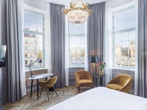a bedroom with a chandelier and a table and chairs at Radisson Collection, Strand Hotel, Stockholm in Stockholm