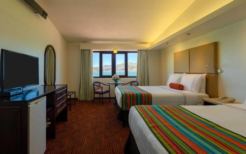 a hotel room with two beds and a flat screen tv at Sonesta Posadas del Inca Puno in Puno
