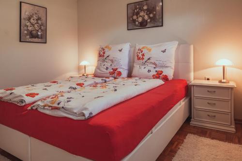 ein Schlafzimmer mit einem roten und weißen Bett mit zwei Lampen in der Unterkunft Gardenia-Altach in Altach