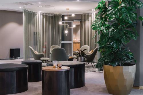 a lobby with chairs and a large potted plant at Scandic Opalen in Gothenburg