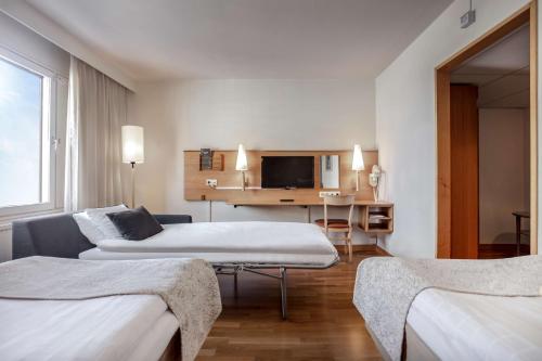 um quarto de hotel com duas camas e uma secretária em Scandic Portalen em Jönköping