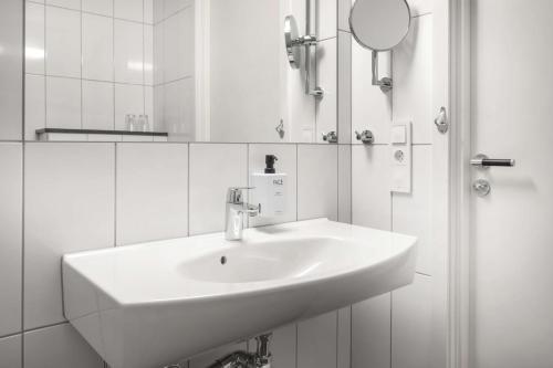 La salle de bains blanche est pourvue d'un lavabo et d'un miroir. dans l'établissement Scandic Linköping Väst, à Linköping