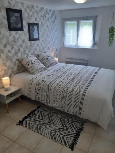 um quarto com uma cama grande com lençóis brancos e almofadas em Gîte la Parent'Aise em Fressenneville
