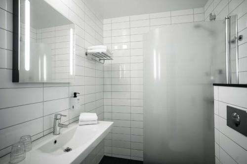 a white bathroom with a sink and a mirror at Scandic Järva Krog in Solna