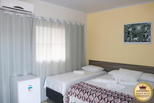 a hotel room with two beds and a window at Pousada Império do Cangaço in Piranhas