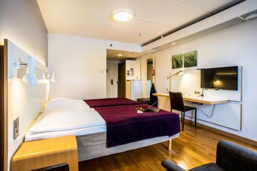 ウメオにあるスカンディック プラザ ウメオのベッド、デスク、テレビが備わるホテルルームです。