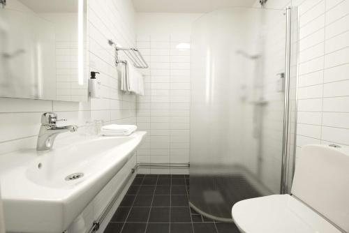 a white bathroom with a sink and a shower at Scandic Örnsköldsvik in Örnsköldsvik