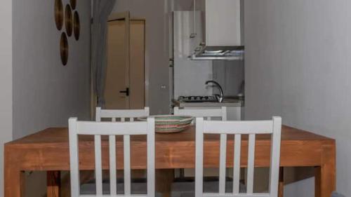 una mesa de madera con 2 sillas blancas y una cocina en Casa Meike, en Sal Rei