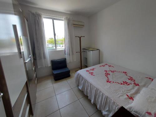 a bedroom with a bed and a chair and a window at Praia da Cachoeira in Florianópolis