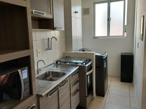 a small kitchen with a sink and a stove at Praia da Cachoeira in Florianópolis