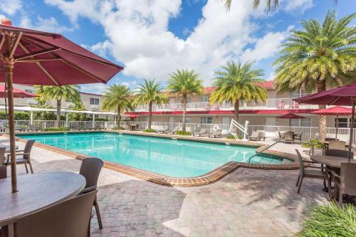 a pool at a hotel with tables and umbrellas at Ramada by Wyndham Miami Springs/Miami International Airport in Miami