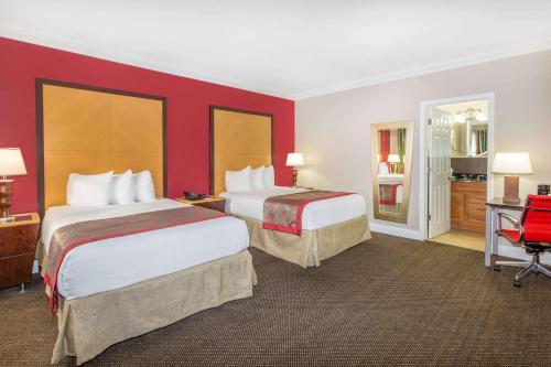 two beds in a hotel room with red walls at Ramada by Wyndham Miami Springs/Miami International Airport in Miami