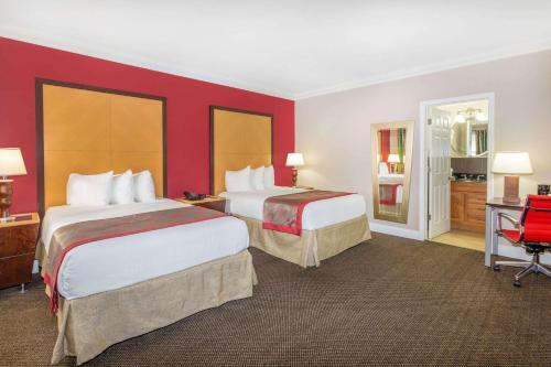 2 camas en una habitación de hotel con paredes rojas en Ramada by Wyndham Miami Springs/Miami International Airport, en Miami