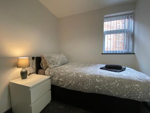 a bedroom with a bed and a dresser and a window at StayCrewe Apartments in Crewe