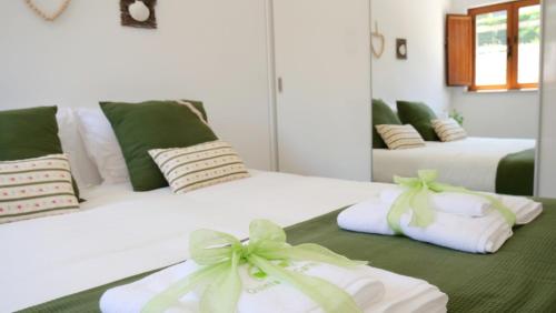 two beds with white towels with green bows on them at Casa Rosa, Quinta Carmo - Alcobaça/Nazaré in Alcobaça