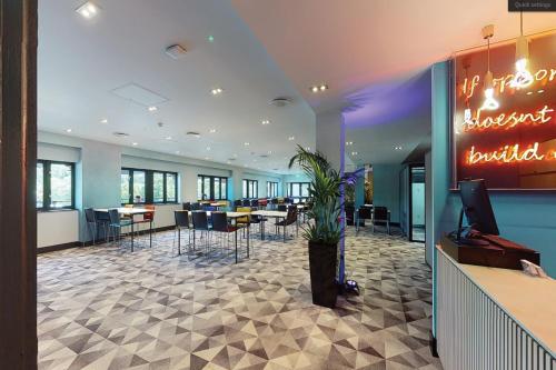 a lobby with a restaurant with tables and chairs at Village Hotel Manchester Bury in Bury