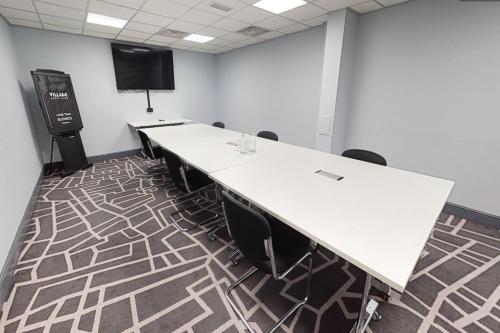 a conference room with a large white table and chairs at Village Hotel Manchester Bury in Bury