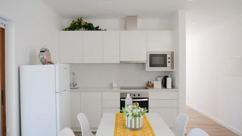 a kitchen with a table and a white refrigerator at Casa Jasmim, Quinta Carmo - Alcobaça/Nazaré in Alcobaça