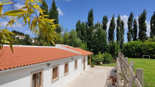 a white building with a red roof and a fence at Casa Jasmim, Quinta Carmo - Alcobaça/Nazaré in Alcobaça