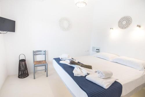a white bedroom with a bed and a chair at Andria's suites in Chrissi Akti