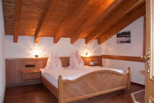 Schlafzimmer mit einem Bett mit weißer Bettwäsche und Holzdecken in der Unterkunft Landhaus Kopp in Oberstdorf