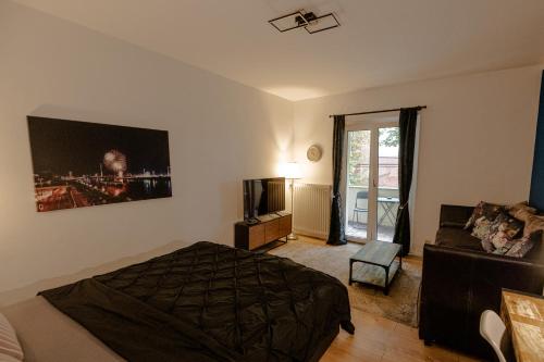 デュッセルドルフにあるダウンタウン スイートのベッドルーム(ベッド1台、ソファ、テレビ付)