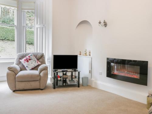 a living room with a chair and a flat screen tv at 6 Coltbridge Gardens in Edinburgh