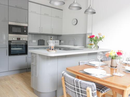a kitchen with white cabinets and a wooden table at 6 Coltbridge Gardens in Edinburgh