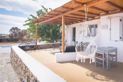 a patio with a table and a swing at Andria's suites in Chrissi Akti