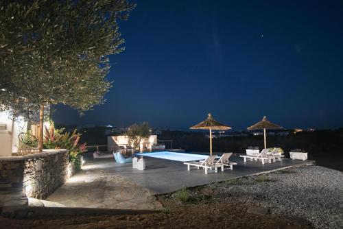 a patio with a pool and umbrellas at night at Andria's suites in Chrissi Akti