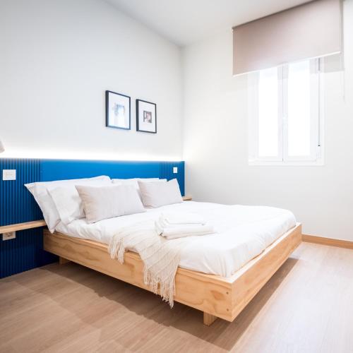 a bed in a room with a blue and white wall at OLBLANC Plaza de España by Batuecas in Madrid