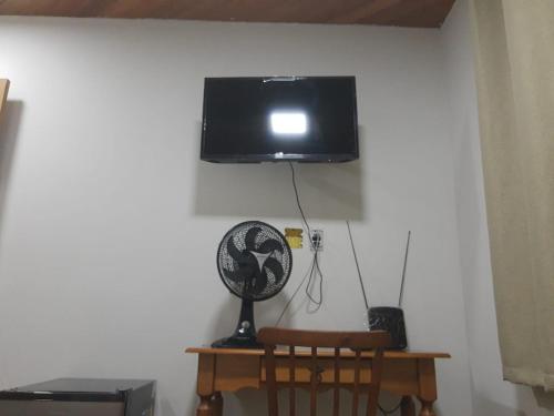 a flat screen tv hanging on a wall with a fan at Suíte Verde in São Pedro da Aldeia