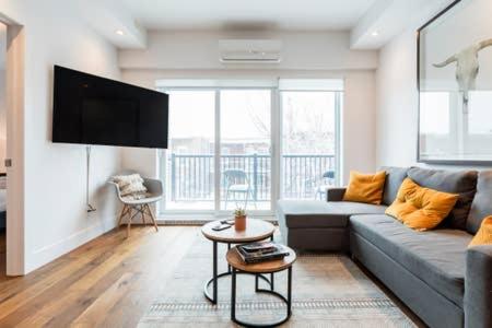a living room with a couch and a flat screen tv at Hip, Stylish Apartment In Little Italy by Den Stays in Montréal