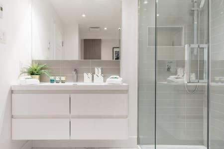 モントリオールにあるHip, Stylish Apartment In Little Italy by Den Staysのガラスのシャワーと洗面台を備えたバスルーム