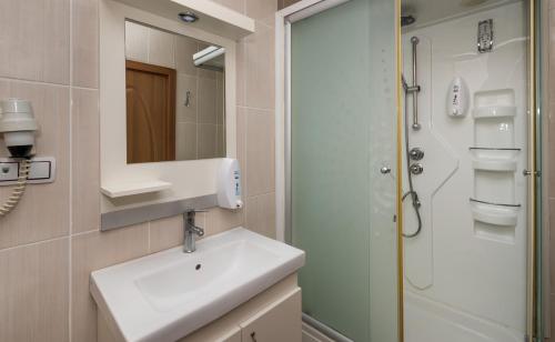 a bathroom with a shower, sink, and mirror at Zel Hotel in Antalya