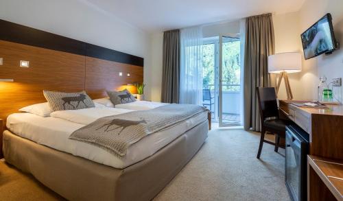 a hotel room with a large bed and a desk at Hotel Residenz Hochalm - Joker Card Partner in Saalbach Hinterglemm