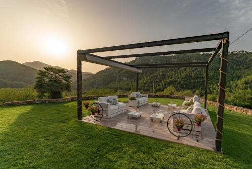 a wooden pergola with couches and chairs in a yard at Hotel Mas Mariassa in Pratdip