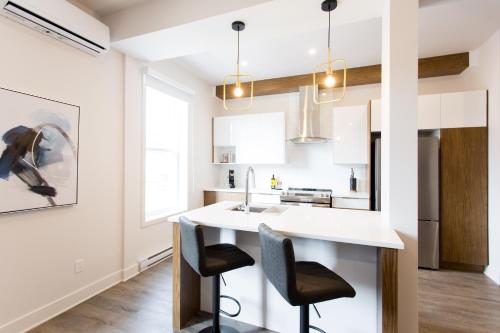 a kitchen with a white counter and two chairs at Huge 2 Bdr with Balcony in Mile End by Den Stays in Montréal