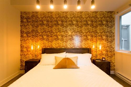 a bedroom with a large white bed with a brick wall at Huge 2 Bdr with Balcony in Mile End by Den Stays in Montréal