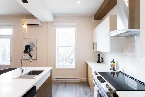 a kitchen with white counters and a sink at Huge 2 Bdr with Balcony in Mile End by Den Stays in Montréal