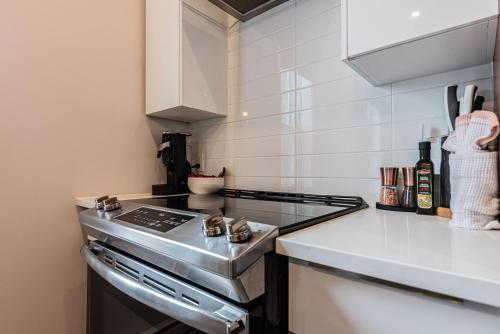 a kitchen with a stove top oven next to a counter at 2 Bedroom Luxury in the Mile End by Den Stays in Montréal