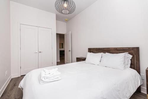 a bedroom with a white bed with towels on it at 2 Bedroom Luxury in the Mile End by Den Stays in Montréal