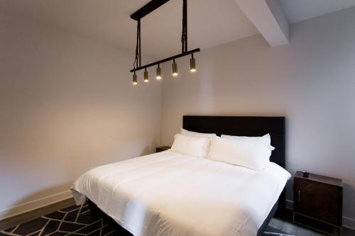 een slaapkamer met een wit bed en een kroonluchter bij Light Filled 2 Bdr Unit in Mile End by Den Stays in Montreal