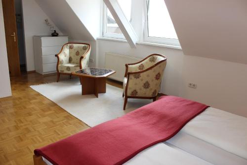 ein Schlafzimmer mit 2 Stühlen, einem Bett und einem Fenster in der Unterkunft Ferienwohnung und Gästezimmer Korb in Krumpendorf am Wörthersee